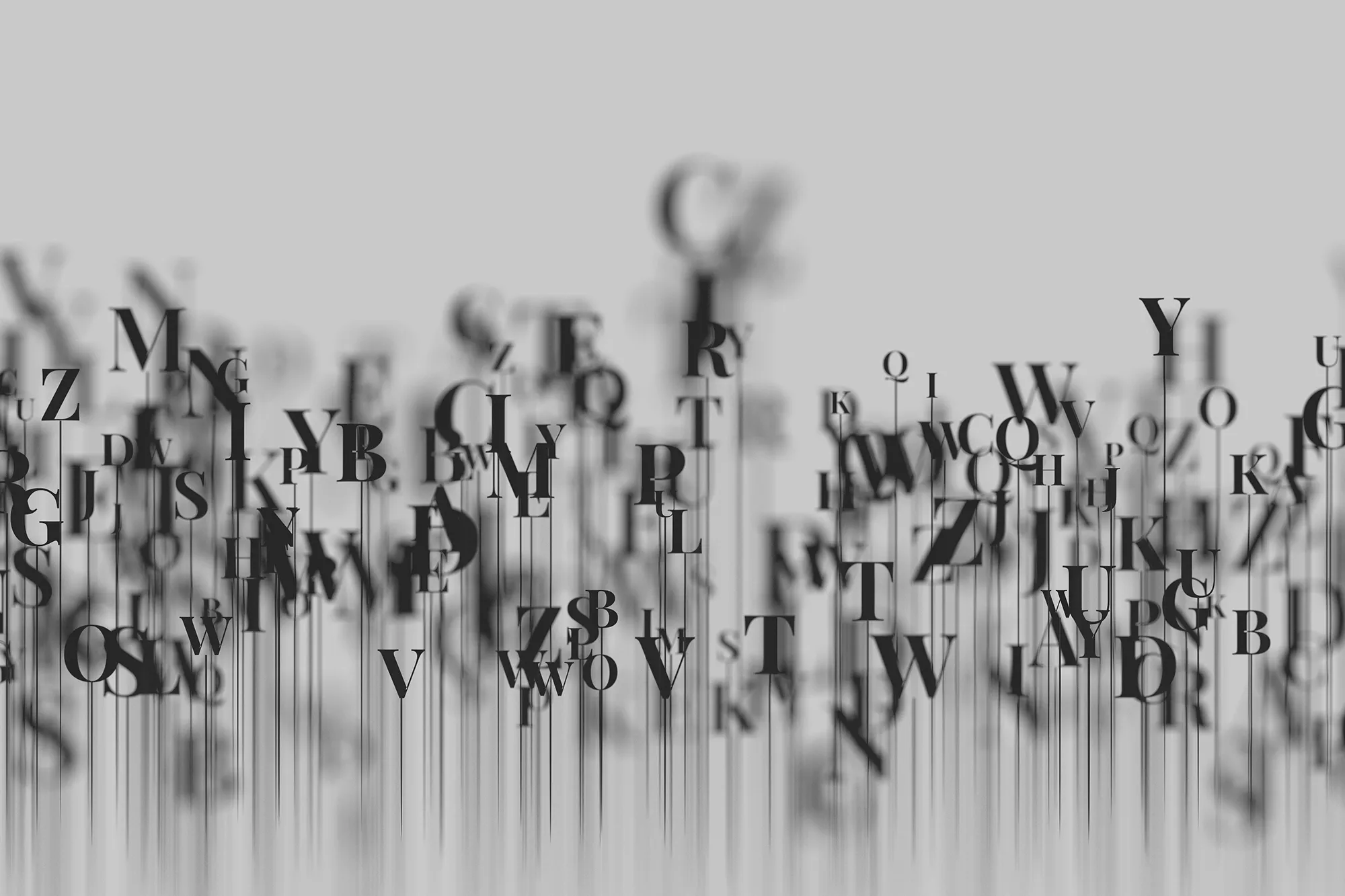 Scattered letters in black with motion blur effect on a light gray background, representing creative writing.