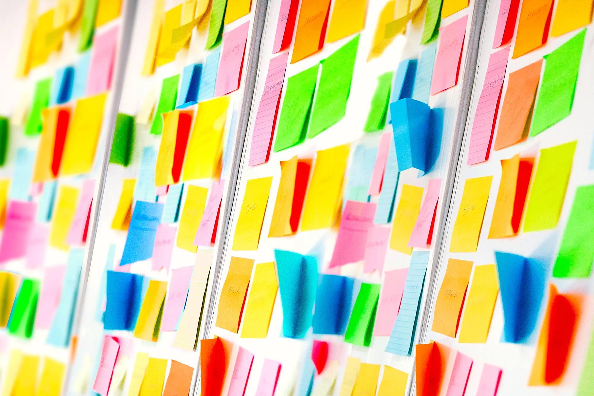 Colorful sticky notes arranged densely on a wall or board, representing brainstorming, creative planning, and design thinking.