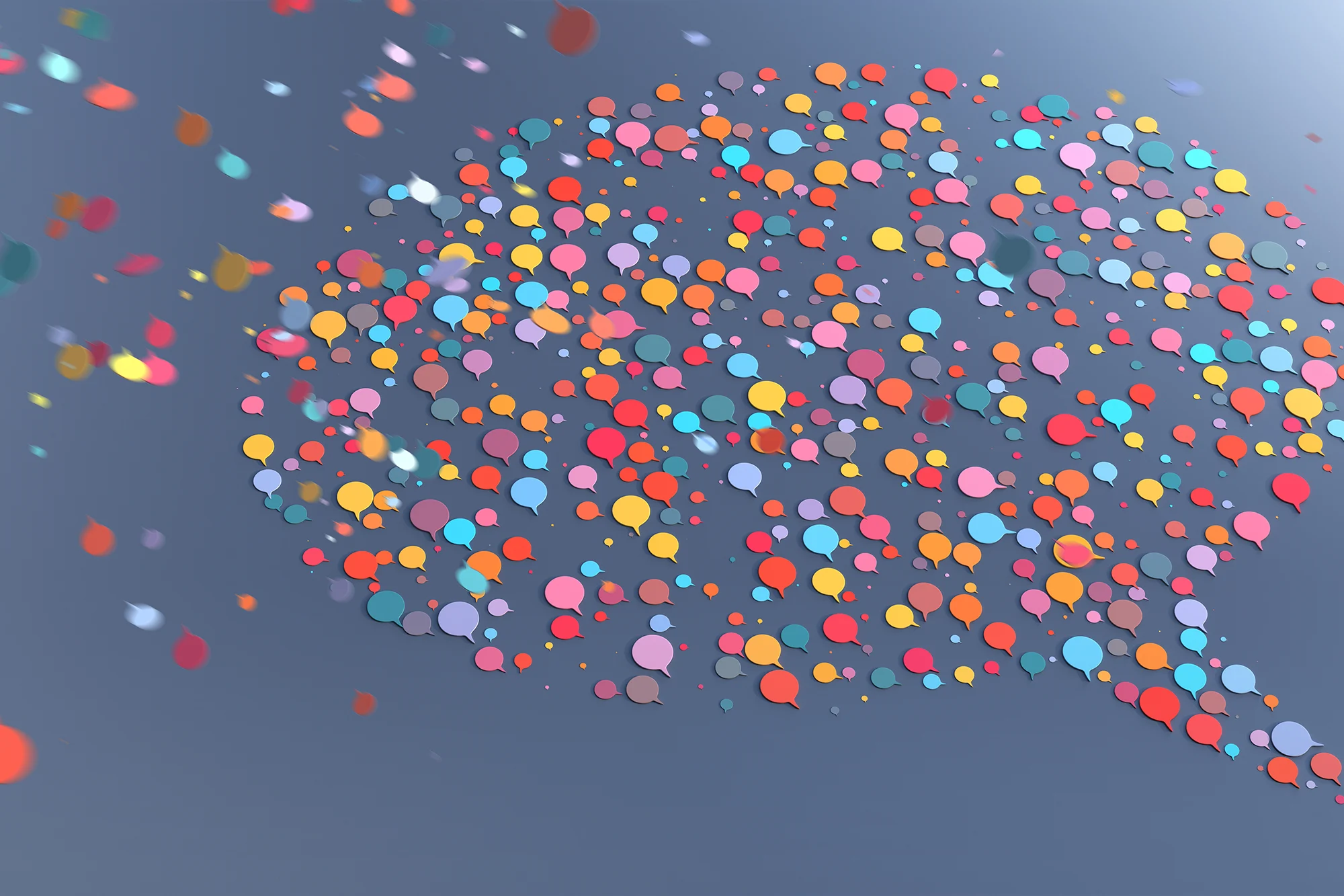 A creative digital illustration of hundreds of small, colorful speech bubbles clustering together to form the shape of one large speech bubble against a dark grey background.